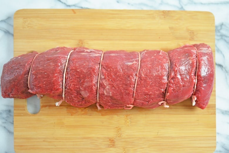 Center cut beef tenderloin tied with butcher's twine on a cutting board 