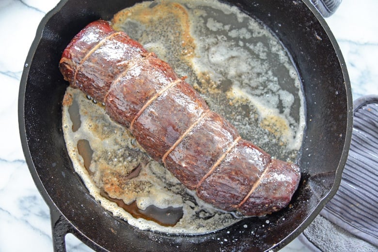 Reverse sear beef tenderloin in a cast iron pan with butter