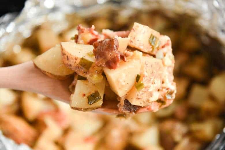 Cheesy crockpot potatoes on a wooden spoon 