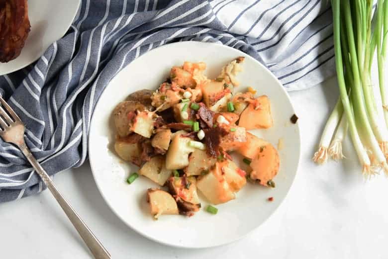 Cheesy potatoes and bacon on a white plate 