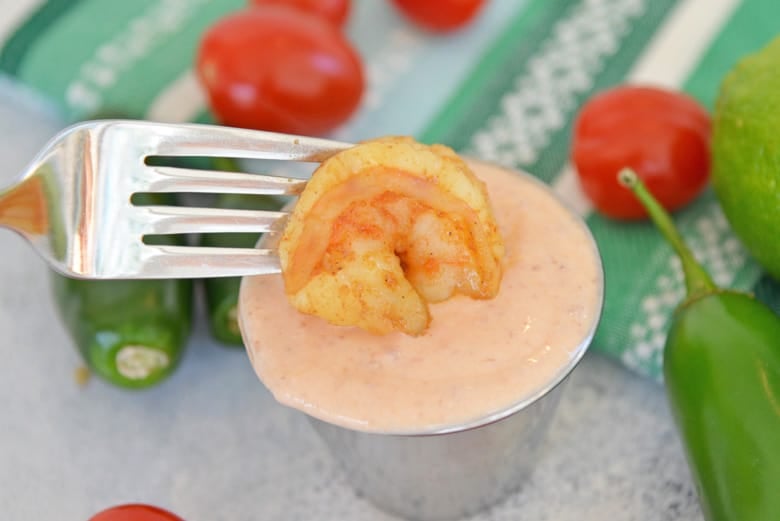 Shrimp dipping into Sriracha sour cream 