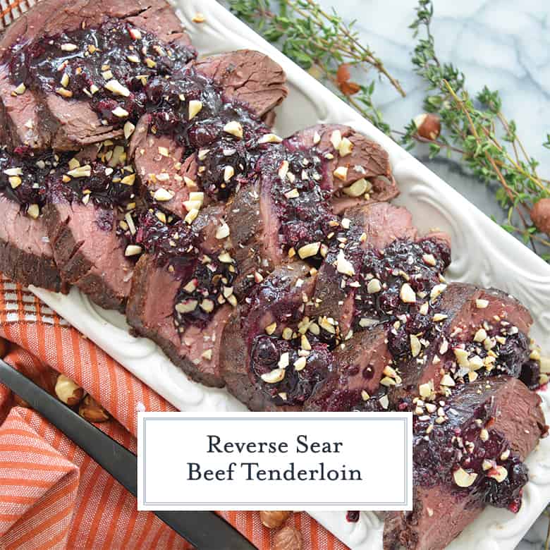 Overhead of sliced reverse sear beef tenderloin with a blueberry sauce and toasted hazelnuts 