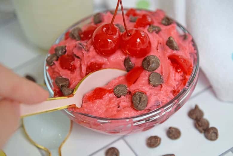 Pink spoon dipping into a bowl of cherry chocolate chip cookie dough 