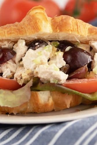 A close up of a sandwich on a plate, with Chicken and Salad