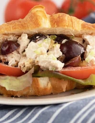 A close up of a sandwich on a plate, with Chicken and Salad
