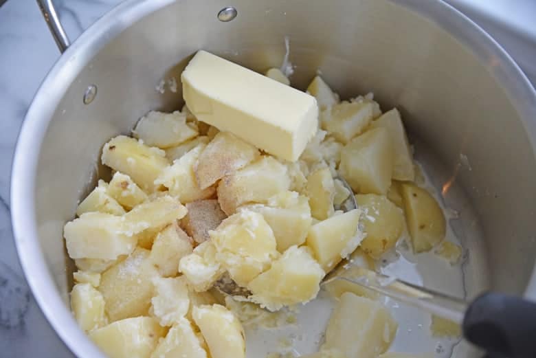 Cooked potatoes in a stock pot with butter, milk and seasonings 