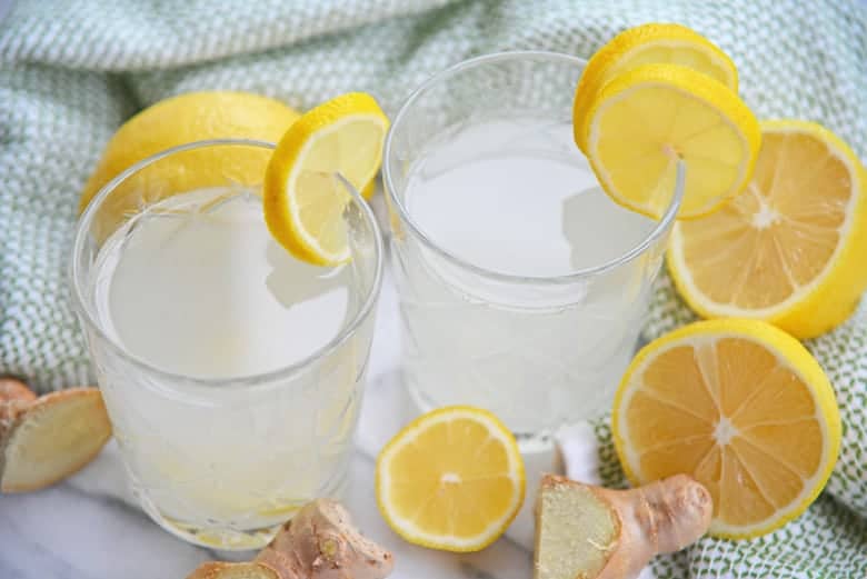 Two glasses of ginger lemon water with fresh lemons 