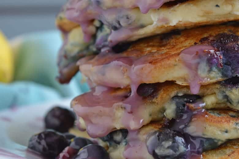 Blueberry syrup running down a stack of pancakes
