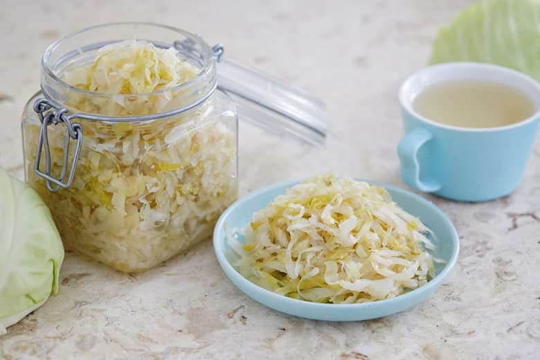 Sauerkraut in a glass jar and on a little blue plate 