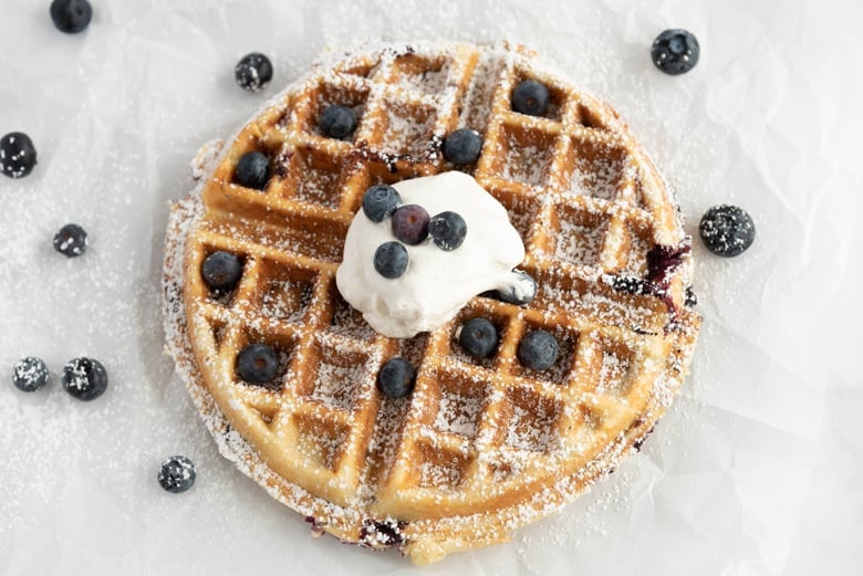 Blueberry waffle with powdered sugar and whipped cream 