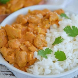 A bowl of rice on a plate, with Butter and Chicken