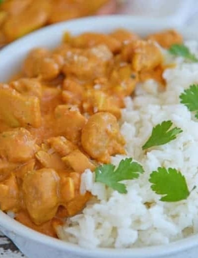 A bowl of rice on a plate, with Butter and Chicken