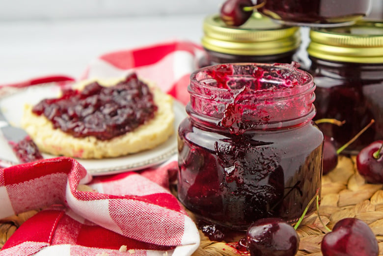 cherry jam in a mason jar and jam on a muffin 