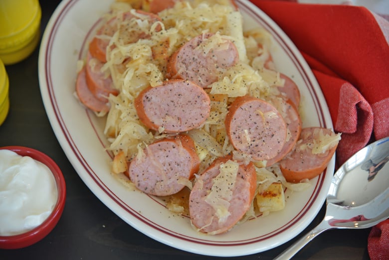 A plate of food on a table, with Kielbasa and Sauerkraut