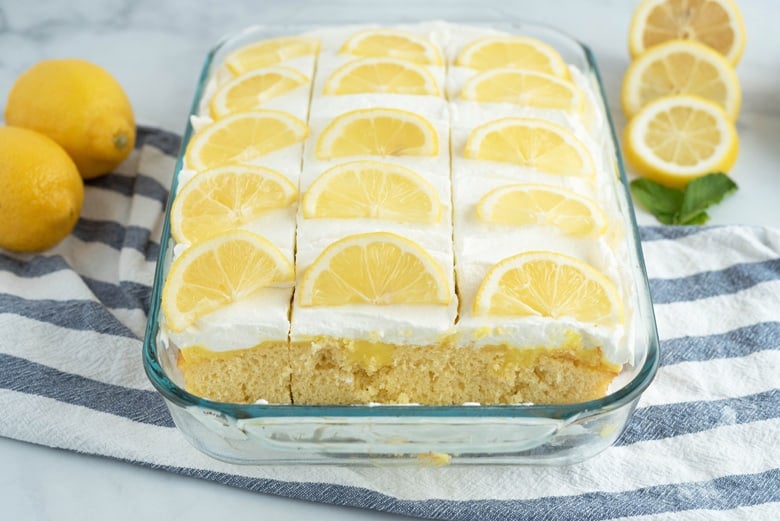 Lemon poke cake decorated with fresh lemon wedges 