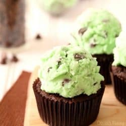angled shot of mint chocolate chip cupcakes on a wooden board