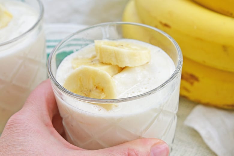 hand grabbing for banana smoothie in a glass 