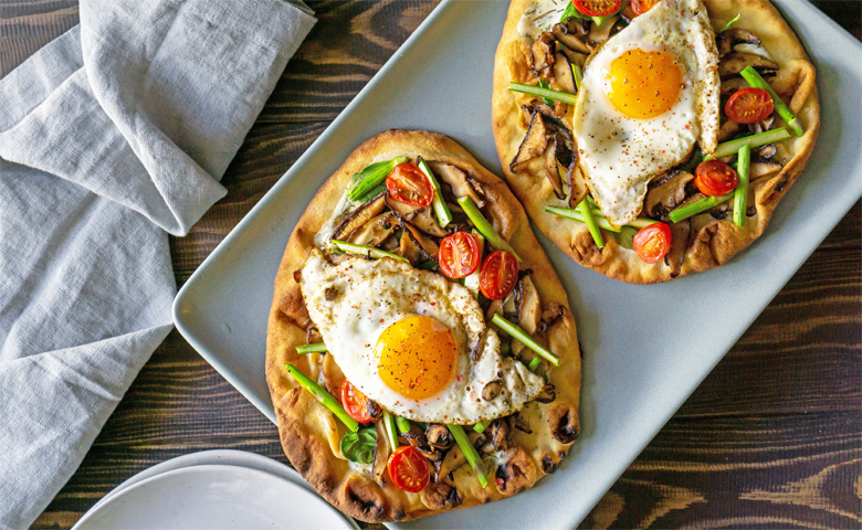 Two individual breakfast pizzas with egg