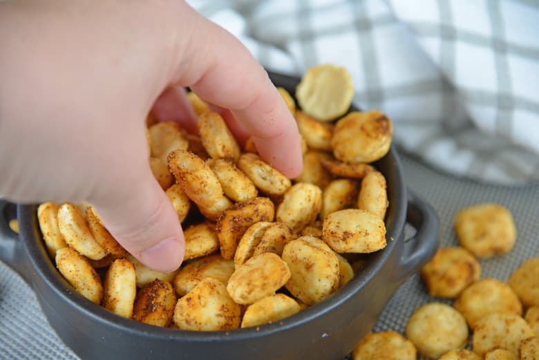 hand getting cajun oyster crackers from a bowl 