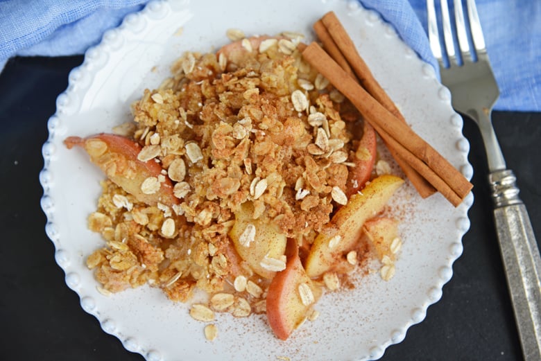 apple crisp on a white plate topped with oats and cinnamon 