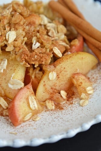 white plate of apple crisp with oatmeal crumble topping