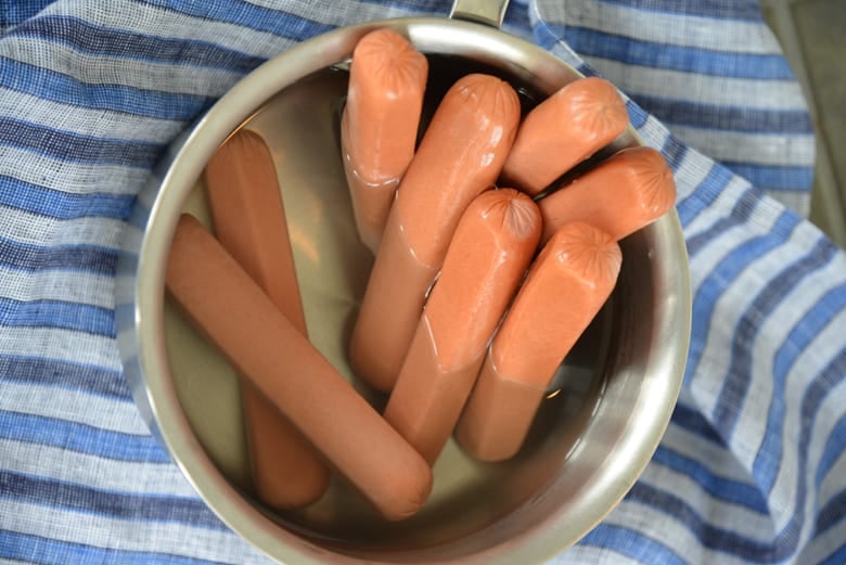 overhead shot of hot dogs in boiling water