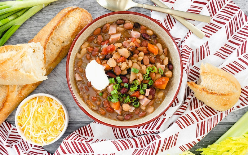 overhead of 15 bean soup in a bowl with bread and cheese