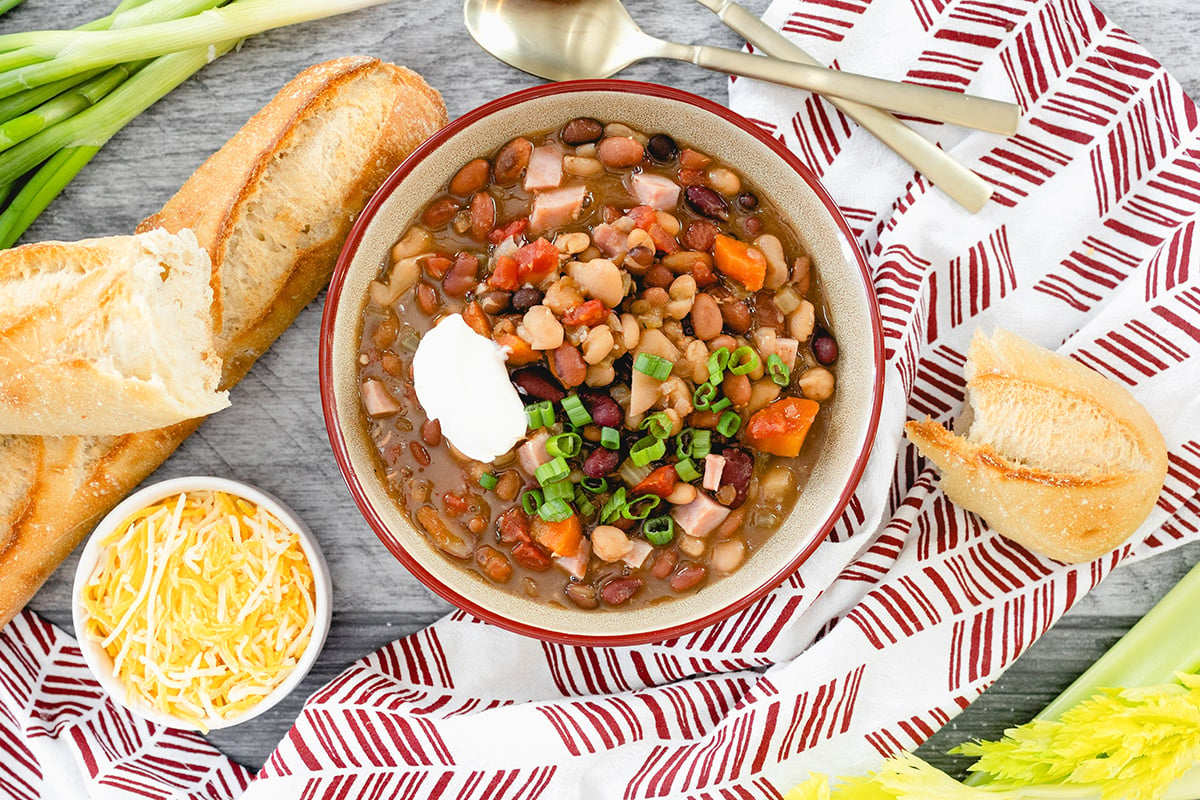 overhead of 15 bean soup in a bowl with bread and cheese