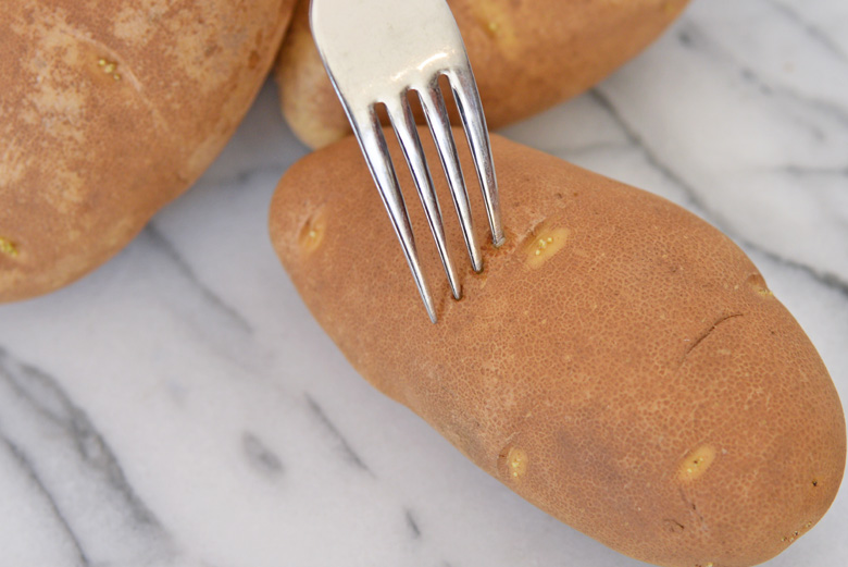 Fork piercing baked potatoes 