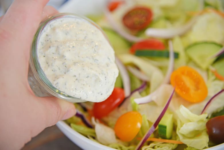light ranch dressing pouring over salad  