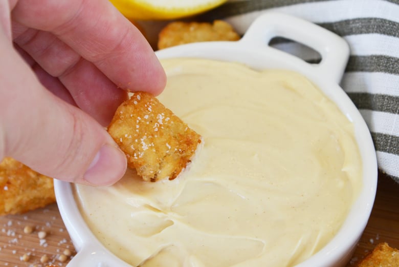 tater tot dipping into mustard sauce 