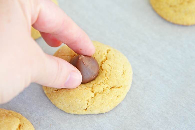 placing a chocolate kiss on a peanut butter cookie 