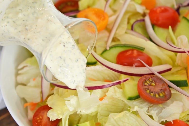 Ranch dressing pouring over fresh salad 