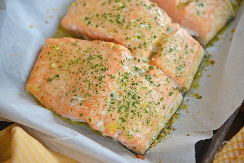 pieces of seasoned salmon on a parchment lined baking sheet 