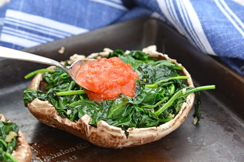 marinara sauce spooning over spinach in a mushroom cap 