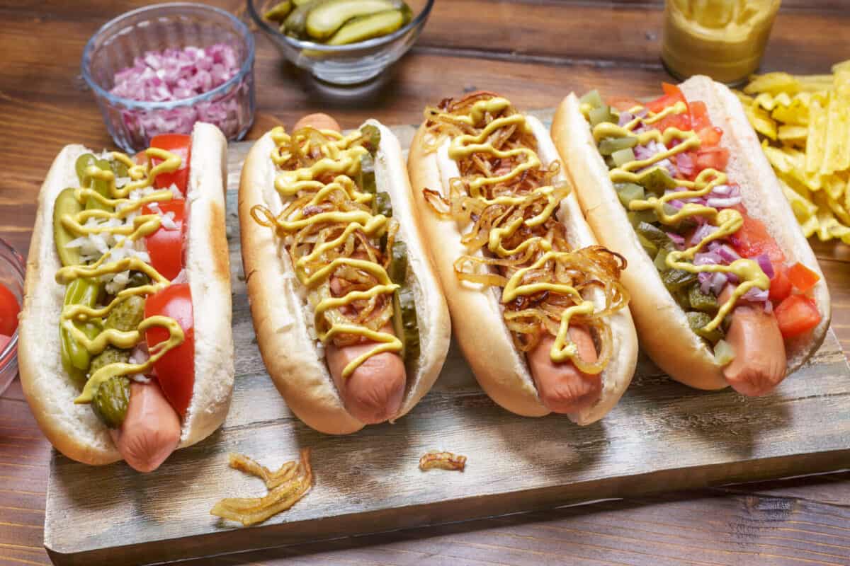 Ein langer Hotdog auf einem Brötchen, das mit Belag bedeckt ist