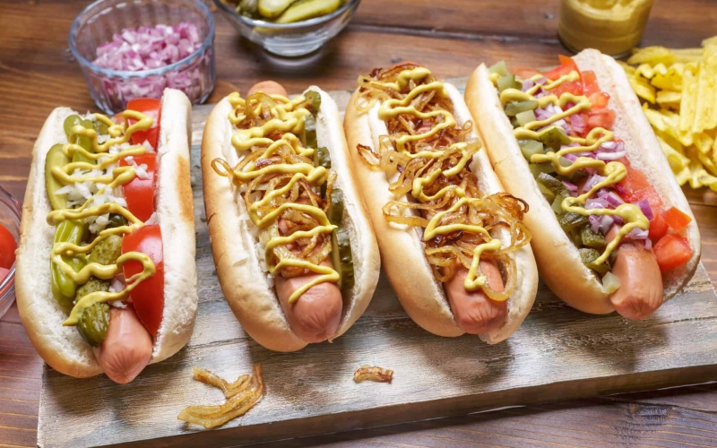 A long hot dog on a bun covered in toppings