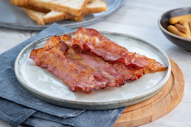 air fryer bacon for breakfast on a plate with blue linen 