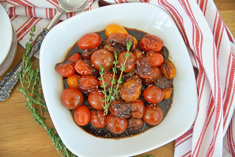 overhead of balsamic stewed tomatoes in a white serving bowl with seasoning