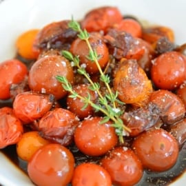 white bowl of stewed tomatoes with thyme garnish