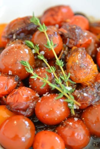 white bowl of stewed tomatoes with thyme garnish