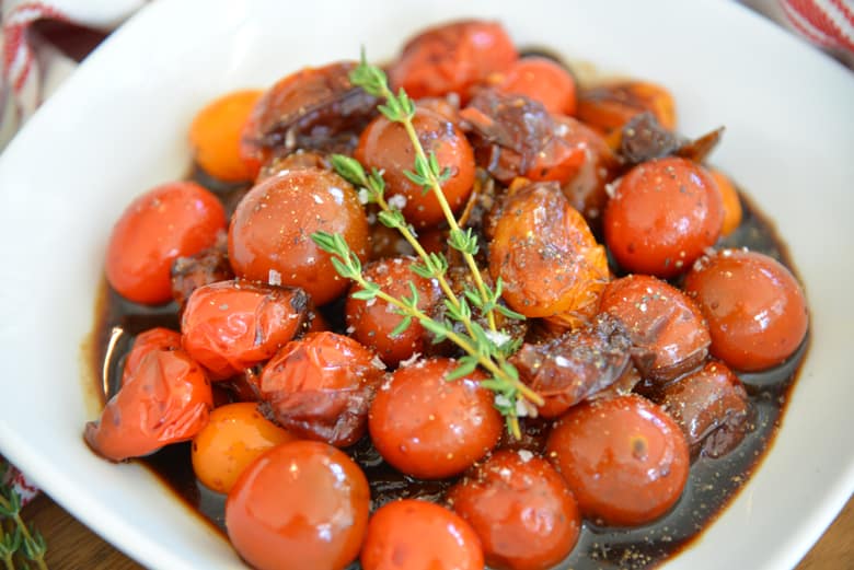 white bowl of stewed tomatoes with thyme garnish