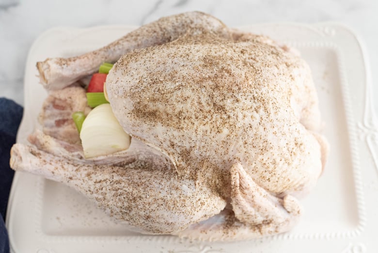 seasoned and stuffed turkey on a white serving platter 