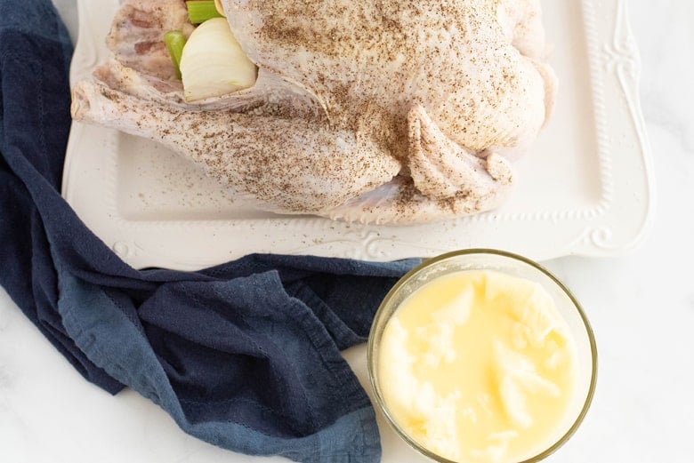 cheesecloth soaking in butter next to a raw turkey 