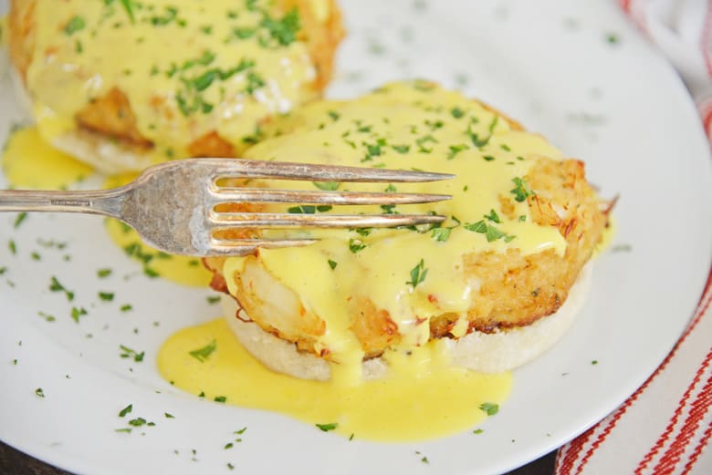 fork cutting into crab cakes hollandaise 