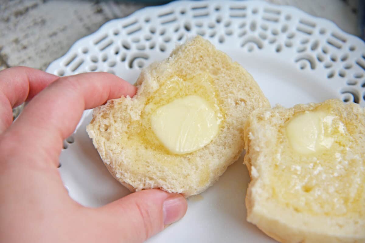 hand reaching in for buttered dinner roll 