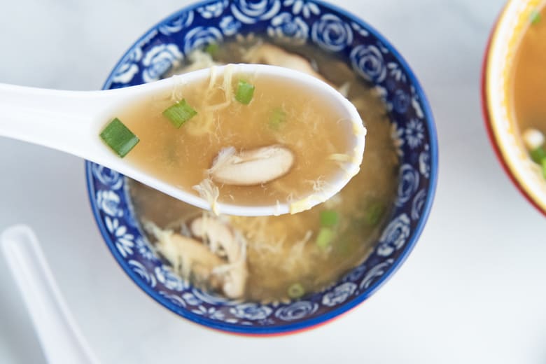 spoon of egg drop soup with mushroom and scallion 