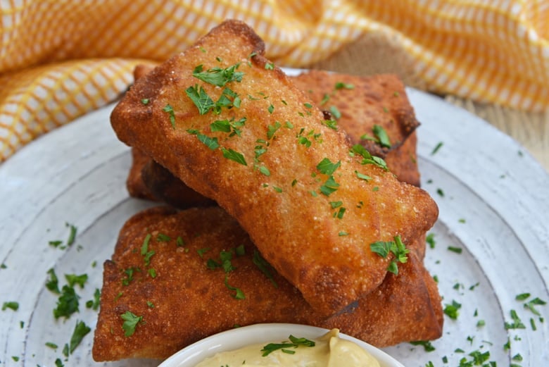 fried german egg rolls on a white serving plate with dipping sauce  