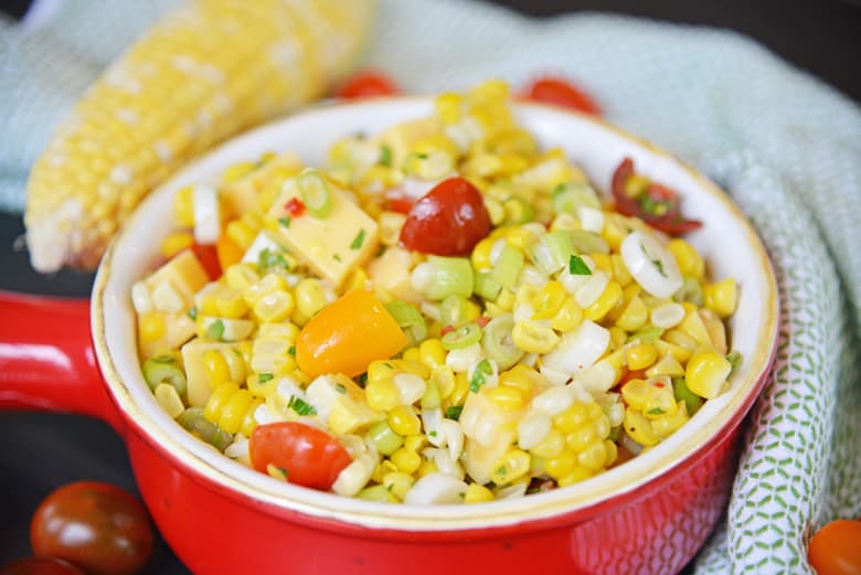 corn salad in a red serving bowl with handle 