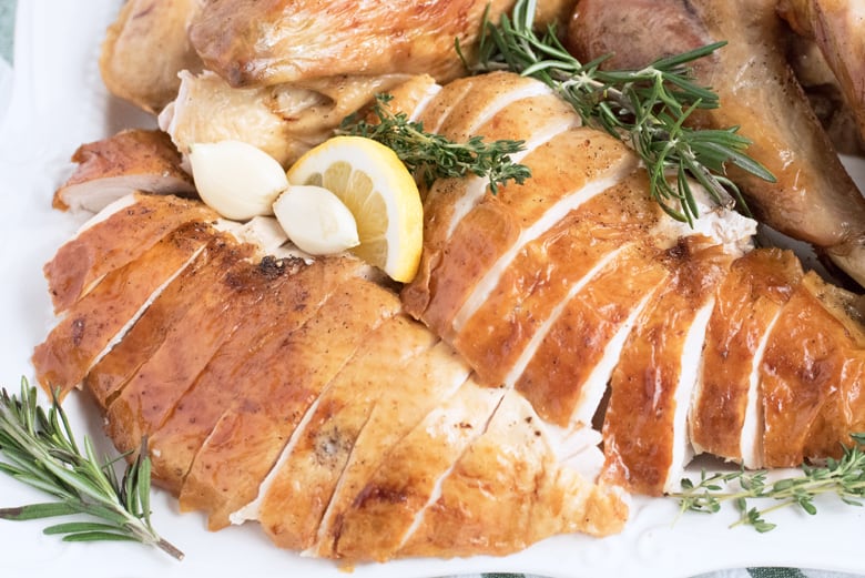 close up of carved turkey breast with herbs and lemon